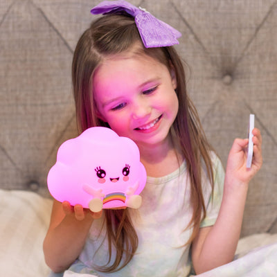 Child with LumiCloud nightlight glowing pink with remote.