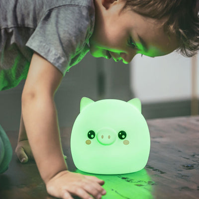 Child with LumiPig nightlight glowing green.