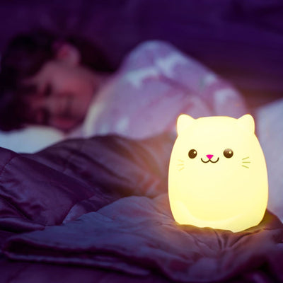 LumiCat nightlight lit up yellow on bed.