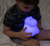 Child holding LumiHippo nightlight while glowing purple.