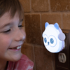LumiGlow owl plugged in and glowing blue with child close by.
