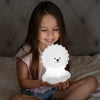 Child holding LumiLion nightlight glowing white.