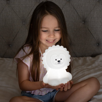 Child holding LumiLion nightlight glowing white.