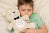 Child sleeping with sound soother bear.